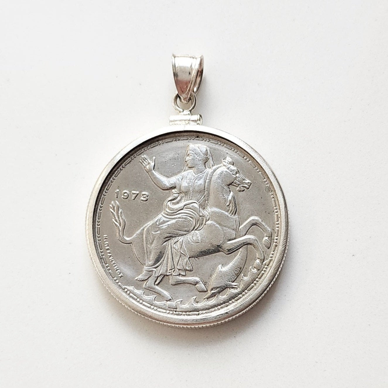 1973 Greek 20 drachma coin of the Moon Goddess Selene riding a horse with a dolphin below.  Set in a sterling silver coin mount.