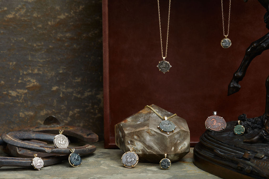 Coin Jewelry collection with ancient Greek and ancient Roman coins set in 18kt gold.  With a rustic background of horseshoes, marble, and a bronze statue